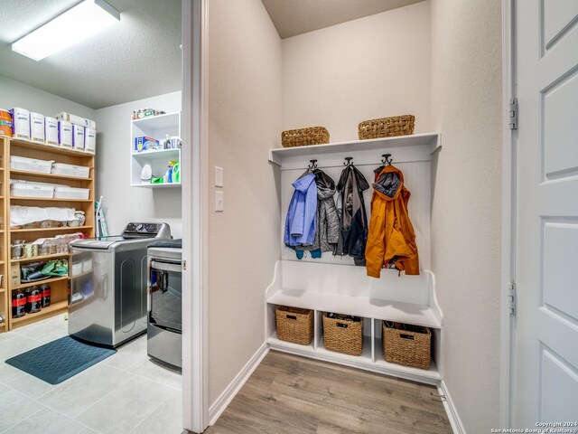 mudroom with washing machine and dryer, a textured ceiling, and light hardwood / wood-style floors