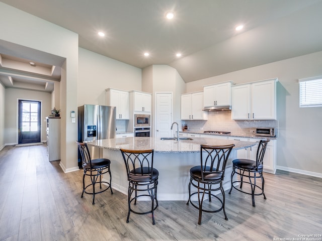 kitchen featuring a center island with sink, appliances with stainless steel finishes, tasteful backsplash, and light wood-type flooring