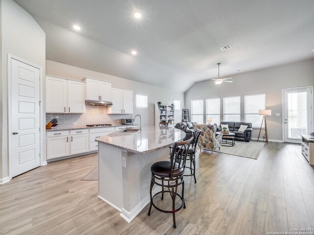 kitchen with a wealth of natural light, white cabinetry, light stone counters, and light hardwood / wood-style floors