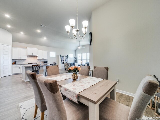 dining room with light hardwood / wood-style flooring and ceiling fan with notable chandelier