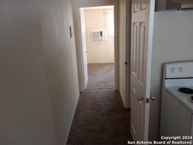 corridor with a wall mounted AC and light carpet