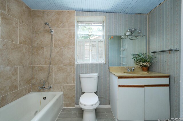 full bathroom with tile patterned flooring, tile walls, tiled shower / bath, toilet, and vanity