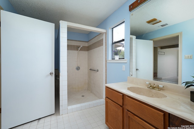 bathroom with tiled shower, vanity, tile patterned floors, and a textured ceiling