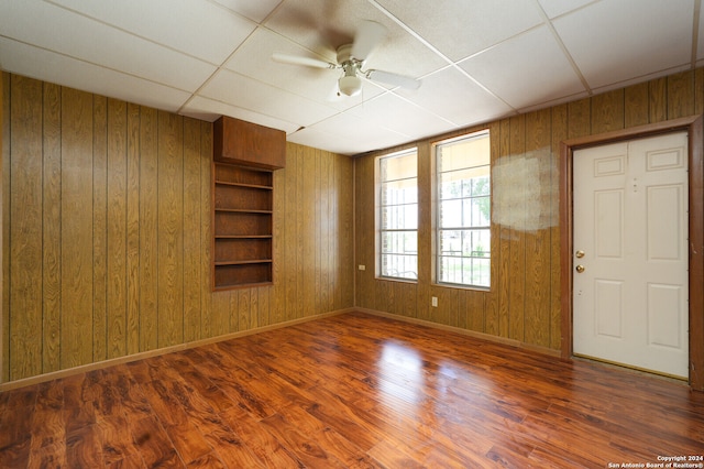 spare room featuring wooden walls, a drop ceiling, and hardwood / wood-style floors