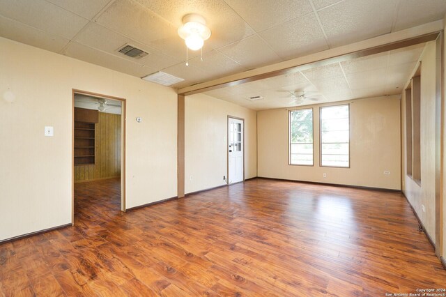 spare room with ceiling fan, hardwood / wood-style flooring, and a drop ceiling