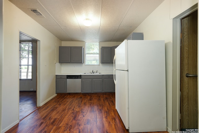 kitchen with stainless steel dishwasher, dark wood-type flooring, white refrigerator, and gray cabinetry