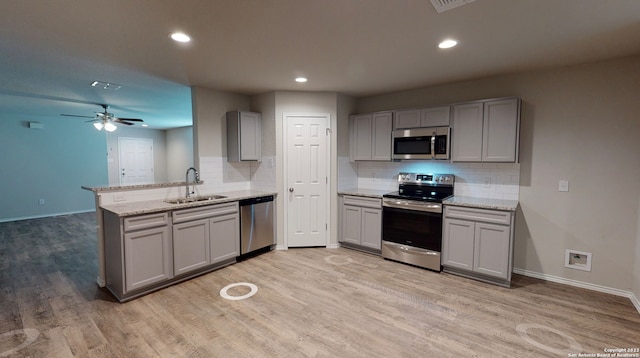 kitchen featuring appliances with stainless steel finishes, gray cabinets, sink, and light stone countertops