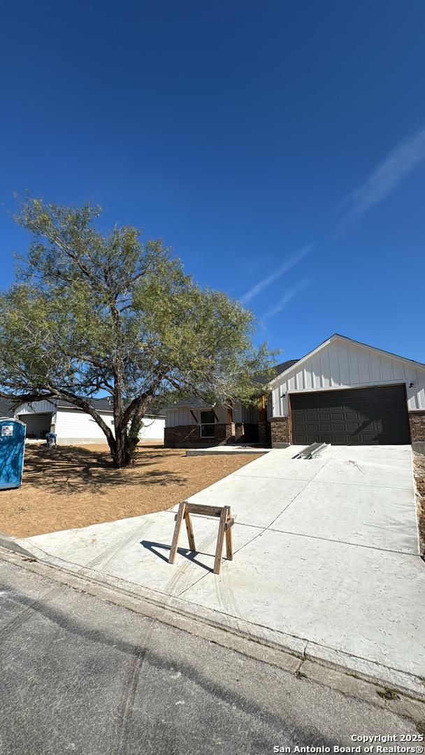 view of front facade featuring brick siding, board and batten siding, and concrete driveway