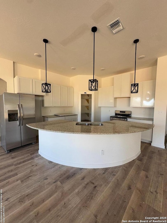 kitchen featuring pendant lighting, appliances with stainless steel finishes, an island with sink, and white cabinets