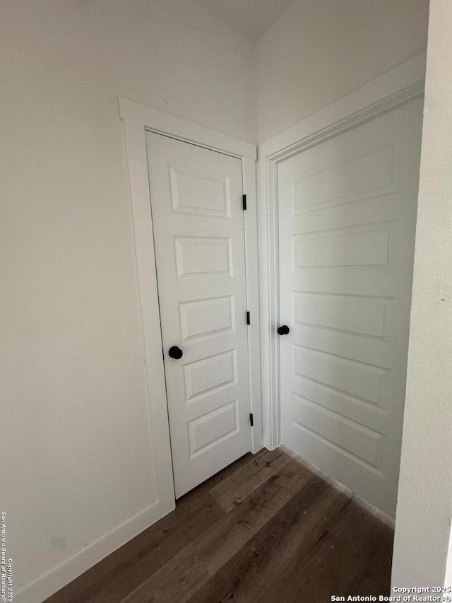 doorway with dark wood-type flooring and baseboards