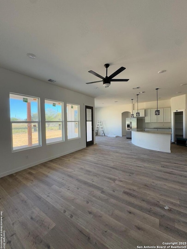 unfurnished living room featuring wood finished floors, visible vents, and a ceiling fan