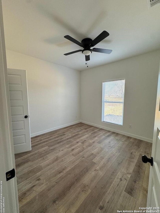 unfurnished room with ceiling fan, baseboards, and wood finished floors