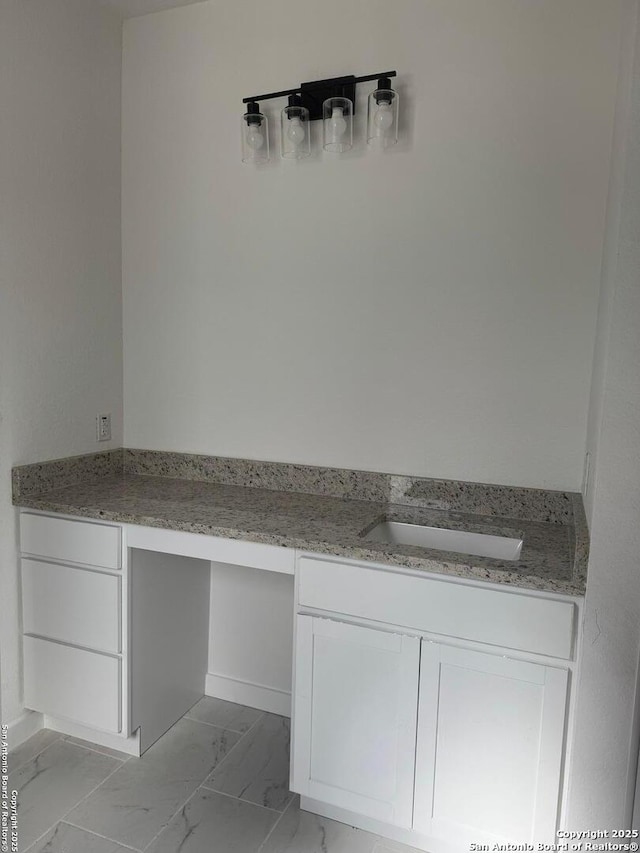 bathroom with marble finish floor and a sink