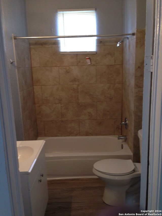 full bathroom with wood-type flooring, toilet, vanity, and tiled shower / bath combo