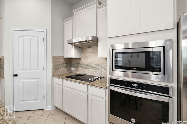 kitchen featuring white cabinets, light stone counters, light tile patterned floors, and appliances with stainless steel finishes