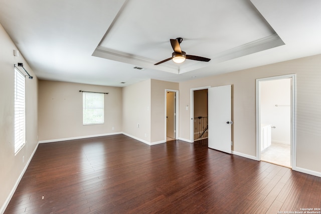 unfurnished bedroom featuring wood-type flooring, a raised ceiling, connected bathroom, and ceiling fan