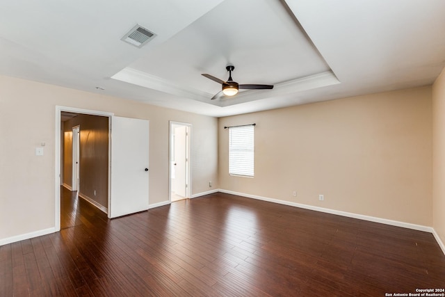 spare room with dark hardwood / wood-style floors, ceiling fan, and a tray ceiling