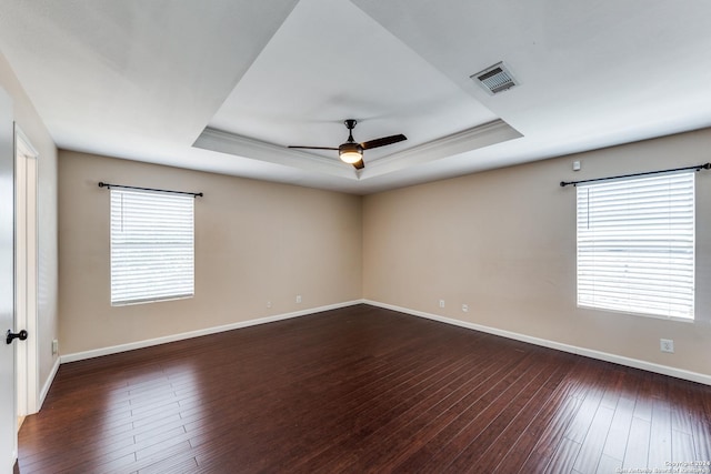 spare room with a raised ceiling, crown molding, dark hardwood / wood-style floors, and ceiling fan