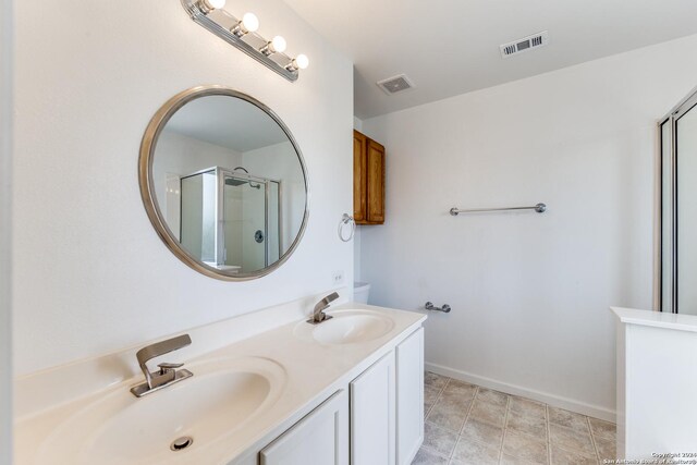 bathroom with a shower with shower door, toilet, double sink vanity, and tile patterned flooring