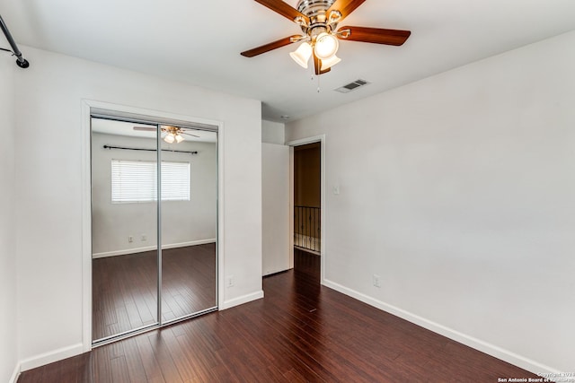 unfurnished bedroom with dark hardwood / wood-style floors, ceiling fan, and a closet