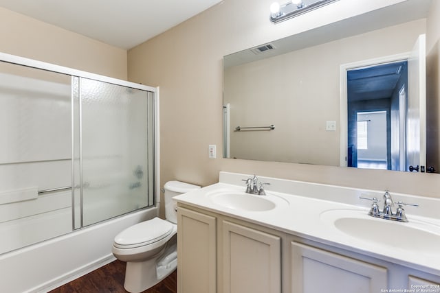 full bathroom featuring toilet, wood-type flooring, combined bath / shower with glass door, and double sink vanity