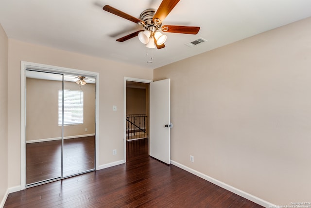 unfurnished bedroom with ceiling fan, dark hardwood / wood-style flooring, and a closet