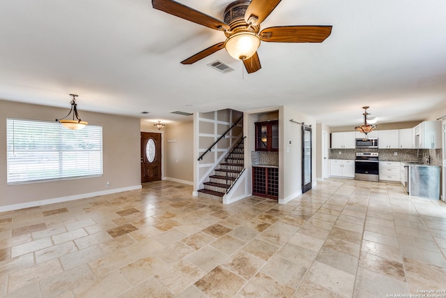 unfurnished living room with a barn door and ceiling fan