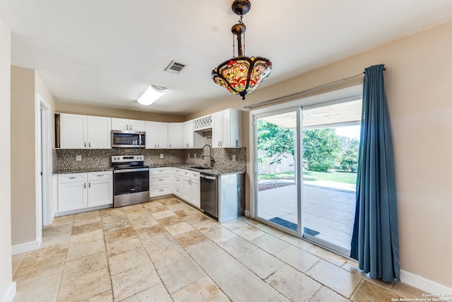 kitchen featuring white cabinets, stainless steel appliances, backsplash, light tile patterned floors, and decorative light fixtures