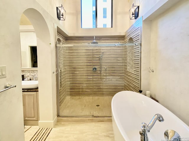 bathroom featuring shower with separate bathtub, backsplash, and vanity