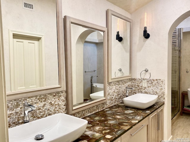 bathroom featuring vanity, an enclosed shower, and decorative backsplash