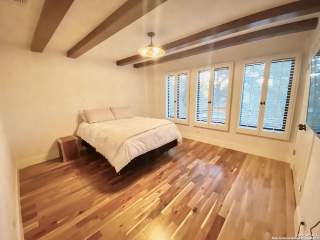 bedroom with hardwood / wood-style flooring, ceiling fan, and beamed ceiling