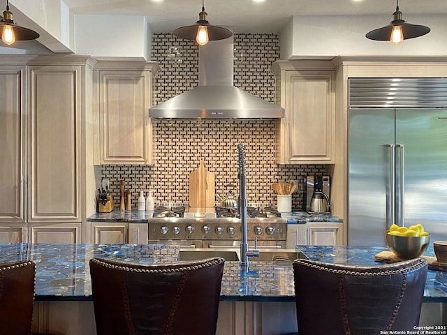 kitchen featuring decorative light fixtures, premium appliances, decorative backsplash, cream cabinets, and wall chimney exhaust hood