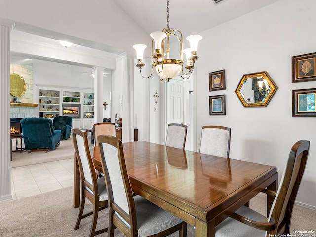 carpeted dining space with decorative columns, an inviting chandelier, built in features, a fireplace, and vaulted ceiling