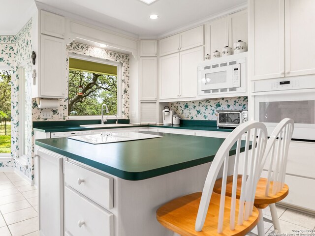 kitchen with light tile patterned flooring, sink, white appliances, and white cabinetry