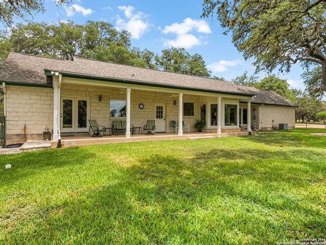 rear view of property with a yard, a patio, and central AC