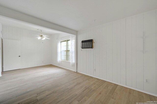 empty room featuring light hardwood / wood-style flooring, ceiling fan, and wood walls