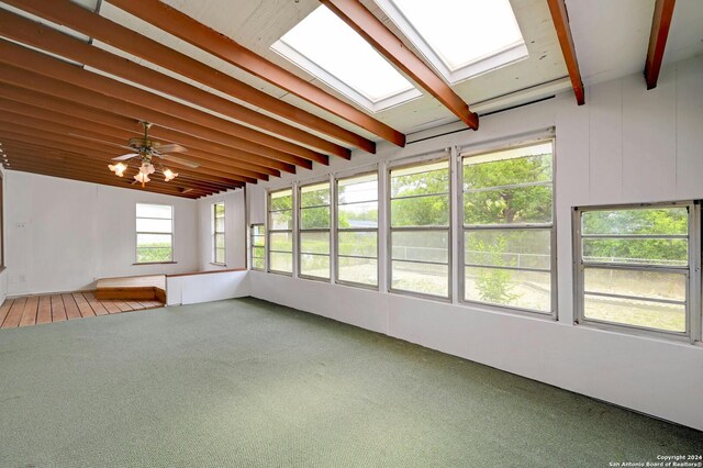 unfurnished sunroom with ceiling fan, beam ceiling, and a skylight