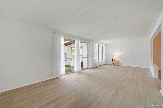 unfurnished room featuring a textured ceiling and light wood-type flooring