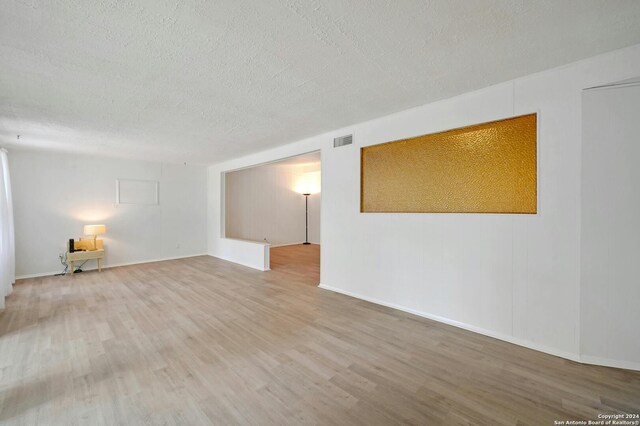 spare room featuring hardwood / wood-style flooring and a textured ceiling