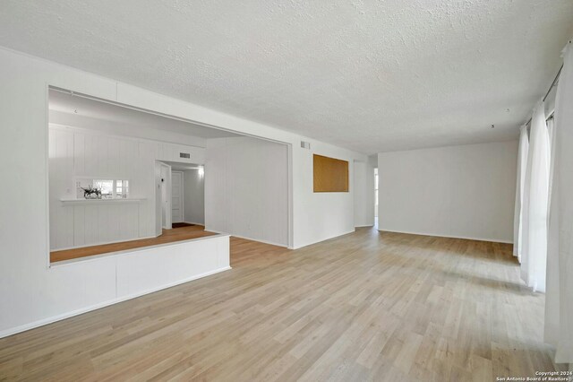 unfurnished living room featuring a textured ceiling and light wood-type flooring