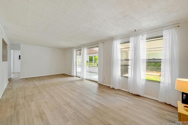 empty room with light hardwood / wood-style flooring and a textured ceiling