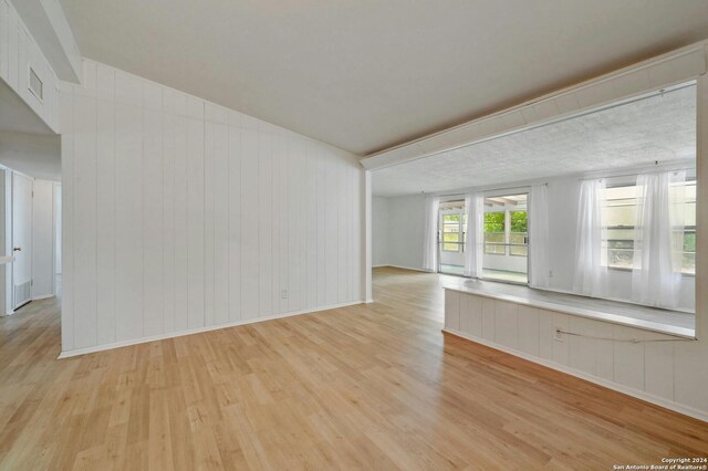 empty room with wood walls and light hardwood / wood-style flooring