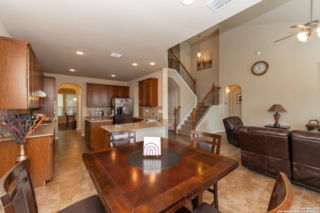 dining room with a high ceiling, ceiling fan, and light tile patterned floors