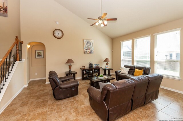 tiled living room with ceiling fan and high vaulted ceiling