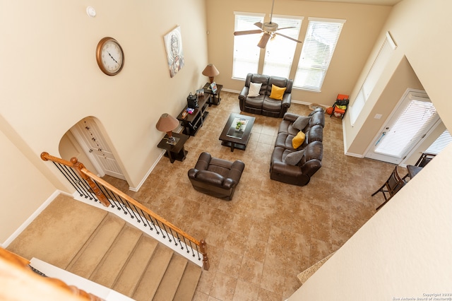 carpeted living room with a high ceiling and ceiling fan