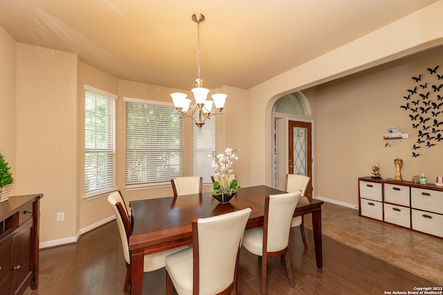 dining space featuring dark wood-type flooring and a notable chandelier