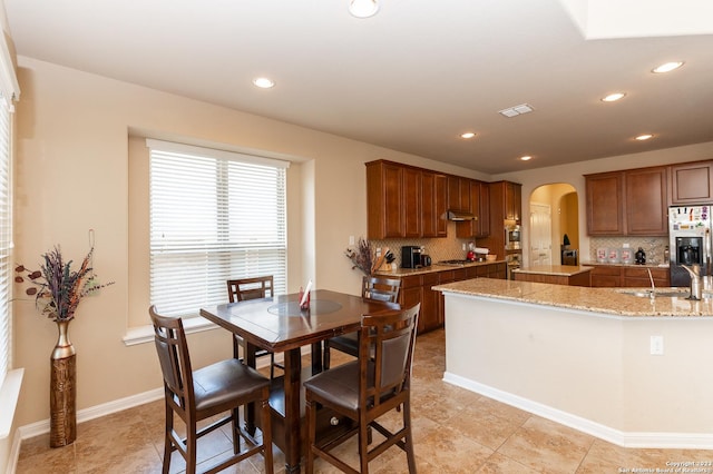 kitchen with appliances with stainless steel finishes, tasteful backsplash, light stone counters, and light tile patterned floors