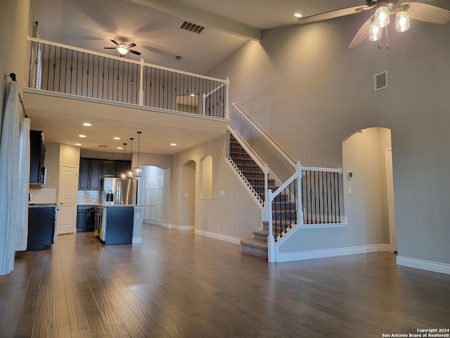 unfurnished living room featuring a high ceiling, ceiling fan, and dark hardwood / wood-style flooring