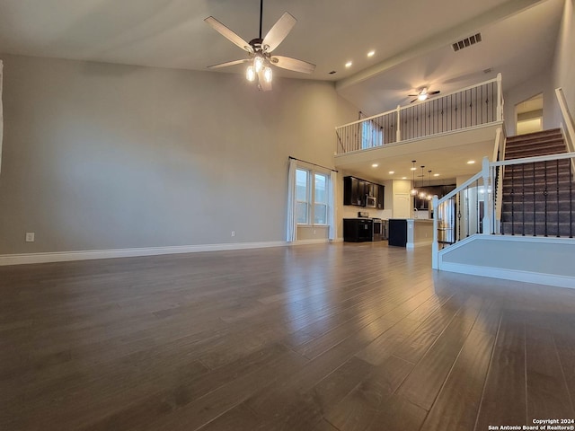 unfurnished living room featuring ceiling fan, a high ceiling, and dark hardwood / wood-style flooring