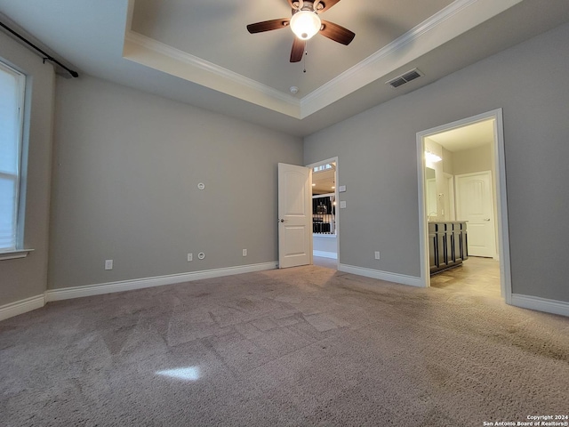 unfurnished bedroom with crown molding, a tray ceiling, and light carpet